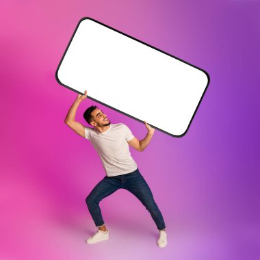 Genç Arap adam elinde büyük, ağır, parlak ışıklı, boş ekranlı bir akıllı telefon tutuyor. Reklam, mobil uygulama veya web sitesi için model