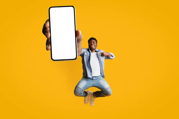 Zorgeloze zwarte man springen met smartphone, mockup — Stockfoto