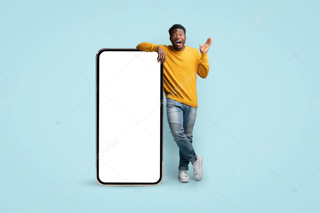 Amazed african american man showing huge cellphone, mockup