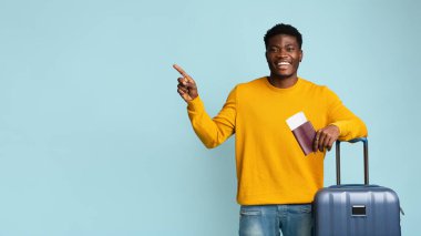 Uçak biletleri ve pasaportu olan gülümseyen bir adam mavi üzerine izole edilmiş.