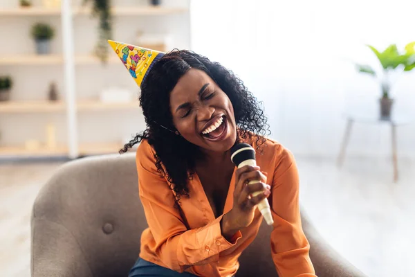 Афроамериканка поет, празднуя день рождения караоке дома — стоковое фото