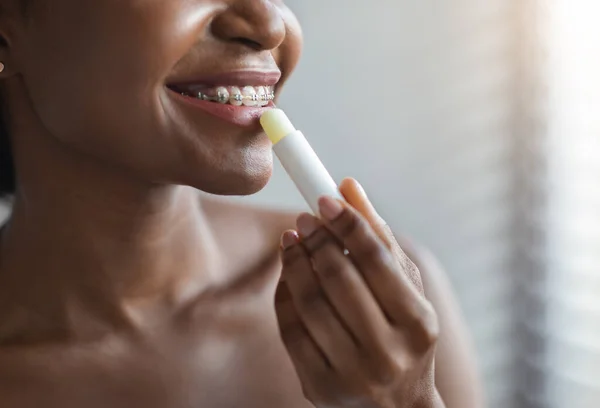 Oigenkännlig afrikansk amerikansk kvinna tillämpa hygieniska läppbalsam — Stockfoto