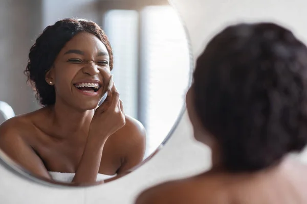 Lachende schwarze Frau oben ohne entfernt Make-up im Badezimmer — Stockfoto
