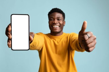 Yakışıklı Afrikalı Amerikalı genç adam cep telefonunu gösteriyor, maket yapıyor.