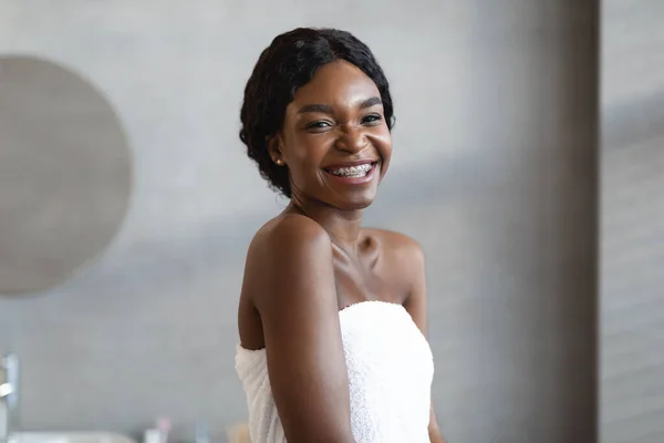 Happy african american woman covered in towel posing at bathroom — Stock Photo, Image