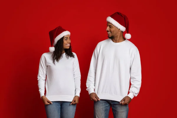 Усміхнений чоловік і жінка в білих светрах і Санта-капелюхах — стокове фото