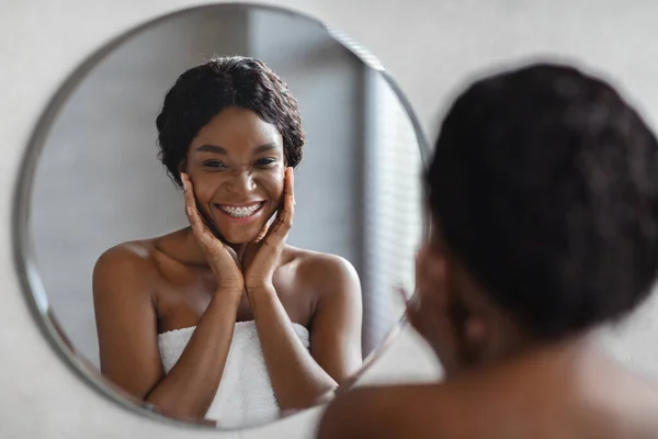 Cermin refleksi wanita muda hitam menerapkan produk wajah — Stok Foto