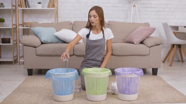 Abfallrecyclingkonzept. Junge positive Hausfrau sortiert im Vorfeld Plastik-, Glas- und Papiermüll in bunte Tonnen — Stockvideo