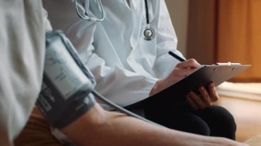 Tanımlanamayan Doktor, içeride yatan yaşlı hasta için atardamar kan basıncını ölçüyor.