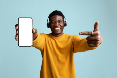 Mutlu siyah adam kulaklık ve akıllı telefon kullanıyor.