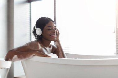 Mutlu Afro-Amerikan bayan banyo yapıyor ve müzik dinliyor.