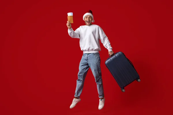 Holiday Travels. Excited Man In Santa Hat Jumping With Suitcase And Tickets — Stock Photo, Image