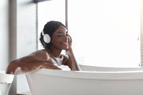 幸せなアフリカ系アメリカ人女性が風呂に入って音楽を聴く — ストック写真