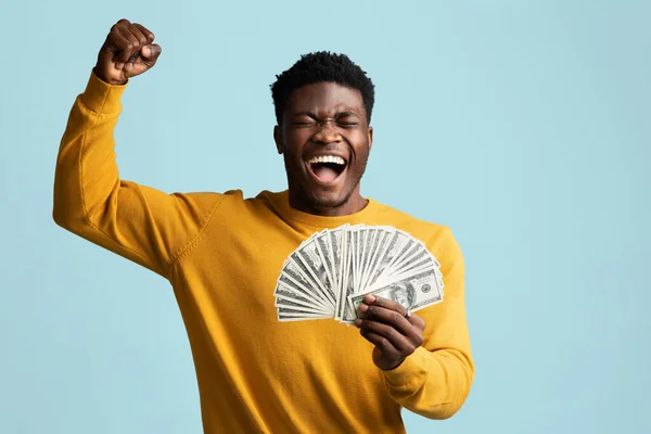 Эмоциональный черный мужчина с кучей денег, поднимающих руку — стоковое фото