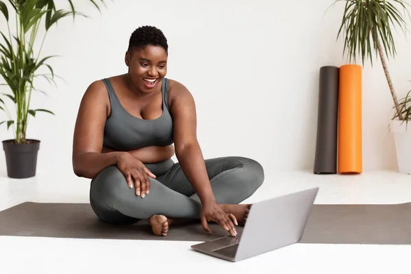 Feliz gorda negra en ropa deportiva asistiendo a clase de fitness online —  Fotos de Stock