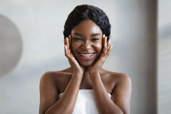 Wanita kulit hitam muda yang bahagia menerapkan produk perawatan mata — Stok Foto