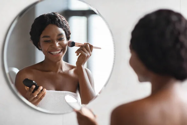 Hermosa dama negra aplicando maquillaje en el baño — Foto de Stock