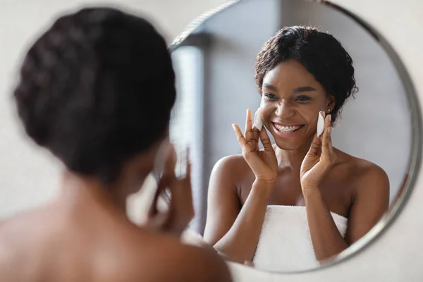 Positieve Afrikaanse Amerikaanse vrouw verwijderen van make-up met katoen pads — Stockfoto
