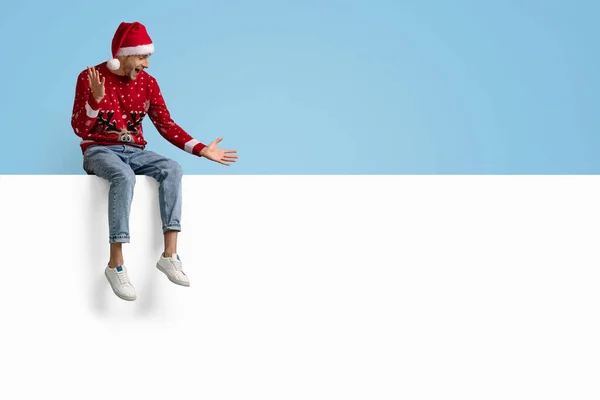 Oferta de Navidad. Chico Emocionado en Santa Sombrero Sentado por encima de la Junta de Publicidad Blanca — Foto de Stock