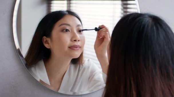 Концепция макияжа. Молодая красивая азиатская женщина Применение тушь возле зеркала в ванной комнате — стоковое видео