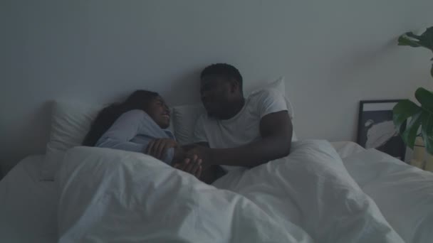 Hermosas tradiciones de pareja. Joven cariñoso afroamericano hombre y mujer acostados en la cama y hablando entre sí — Vídeo de stock