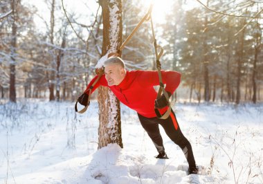TRX uzaklaştırma eğitimi. Kış parkında spor malzemeleriyle spor yapan son sınıf öğrencisi.
