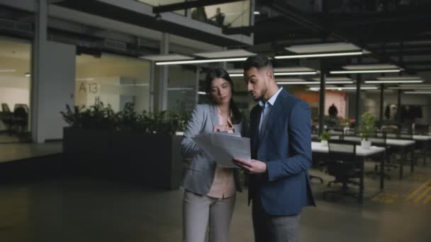 Junge selbstbewusste kaukasische Frau und arabischer Mann Mitarbeiter diskutieren Geschäftsdokumente im modernen Büro, Kamerafahrt — Stockvideo