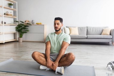 Bin yıllık barışçıl Arap adam nilüfer çiçeği pozunda oturuyor, evde gözleri kapalı meditasyon yapıyor, uzayı kopyalıyor.
