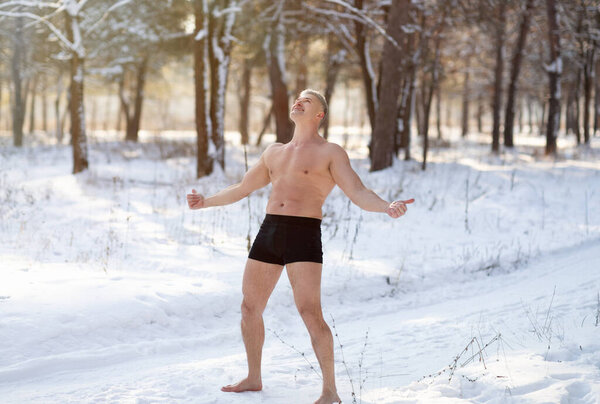Strong senior man exposing himself to cold weather, standing in underwear at snowy park, full length