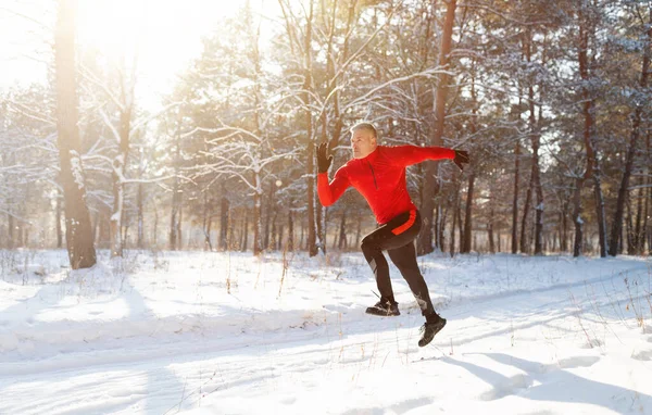 Seasonal sports and activities. Full length of sporty mature man jogging outside in sunny winter park, blank space — Stock Photo, Image