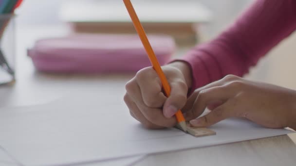 Завдання геометрії. Крупним планом знімок невпізнаваної чорної дівчини малює пряму лінію з олівцем і лінійкою, роблячи домашнє завдання — стокове відео