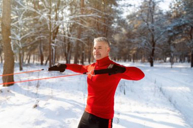 İşlevsel egzersiz. Güçlü olgun sporcu soğuk karlı bir günde parkta vücut ağırlığı direnciyle egzersiz yapıyor.