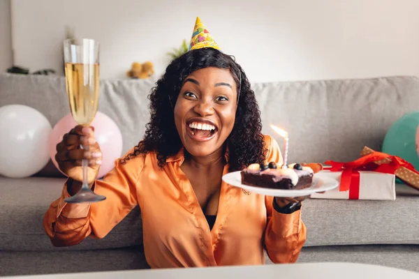 Neşeli siyahi kadın doğum günü pastası ve evde cam tutuyor. — Stok fotoğraf