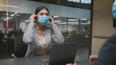 Yeni normal ve koruyucu önlemler. Genç bayan danışman tıbbi maske takıyor ve erkek müşteriyi selamlıyor.