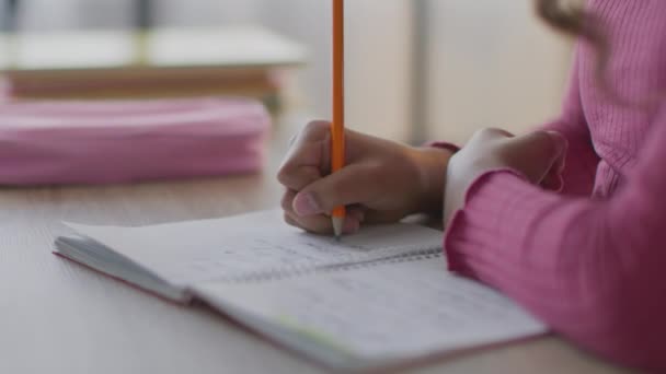 Діти та освіта. Крупним планом маленька невпізнавана чорна школярка пише вправи іноземною мовою в копіювальній книзі — стокове відео