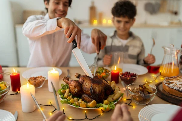 Feliz padre cortando pavo asado de Navidad para su hijo y su familia en la mesa de servicio festivo en el interior, enfoque selectivo — Foto de Stock