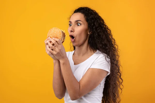 Engraçado latina senhora segurando hambúrguer no estúdio — Fotografia de Stock