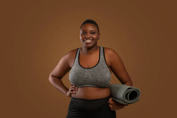 Gordito negro mujer holding yoga mat en estudio — Foto de Stock