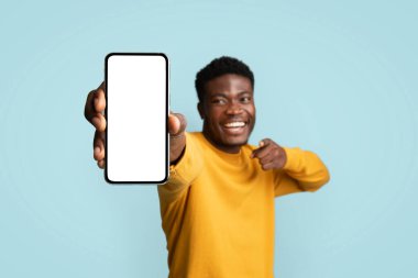 Neşeli Afrikalı Amerikalı genç adam cep telefonunu gösteriyor.