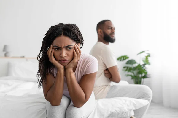 Rozrušený tisíciletý africký americký manželka ignoruje uražený manžel na bílém lůžku v minimalistický ložnice — Stock fotografie