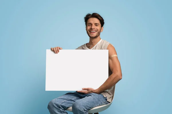 Campaña de Inmunización. Joven con vendaje adhesivo en el brazo que sostiene la placa en blanco —  Fotos de Stock