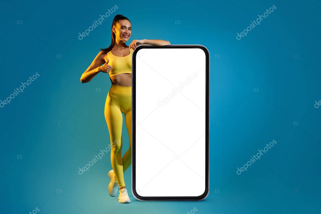 Fitness Lady Leaning On Phone Screen Gesturing Thumbs-Up, Blue Background