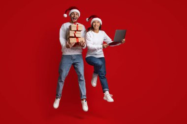 Xmas Teklif. Laptop ve hediye kutularıyla havaya zıplayan neşeli çift