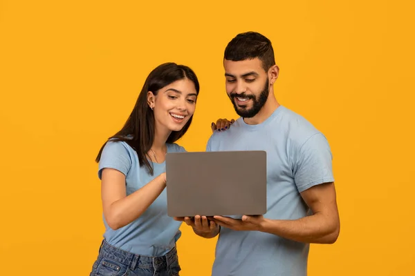 Online εκπαίδευση, ιδέα για ψώνια. Ευτυχισμένο ζευγάρι της Μέσης Ανατολής κοιτάζοντας το laptop και επιλέγοντας την αγορά ή ρολόι μάθημα — Φωτογραφία Αρχείου
