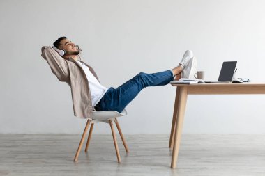 Asyalı adam kulaklık takıp müzik dinliyor.