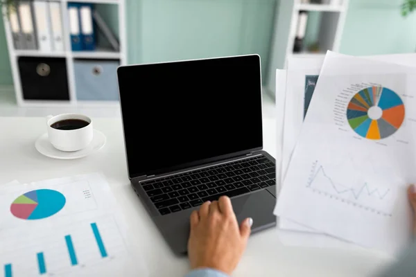 Vrouwelijke financiële manager werkt op laptop computer met blanco scherm en het doen van papierwerk, zittend op de werkplek — Stockfoto