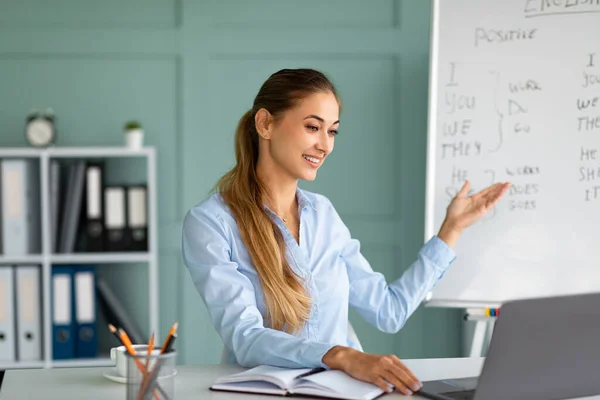 Millennial female English teacher having video conference chat with students, talking to laptop webcamera — Stock fotografie