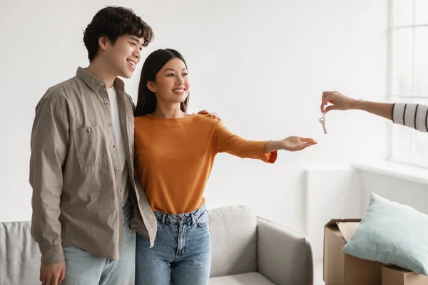 Feliz millennial pareja asiática tomando su nueva llave de la casa de la casera o vendedor de casa en el día de la mudanza. Propiedad de la casa —  Fotos de Stock