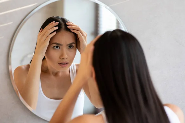 Besorgte langhaarige Chinesin überprüft ihre Haare — Stockfoto