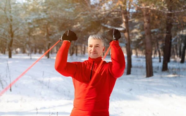 Ajuste hombre maduro ejercicio con correas de suspensión en el parque de invierno —  Fotos de Stock